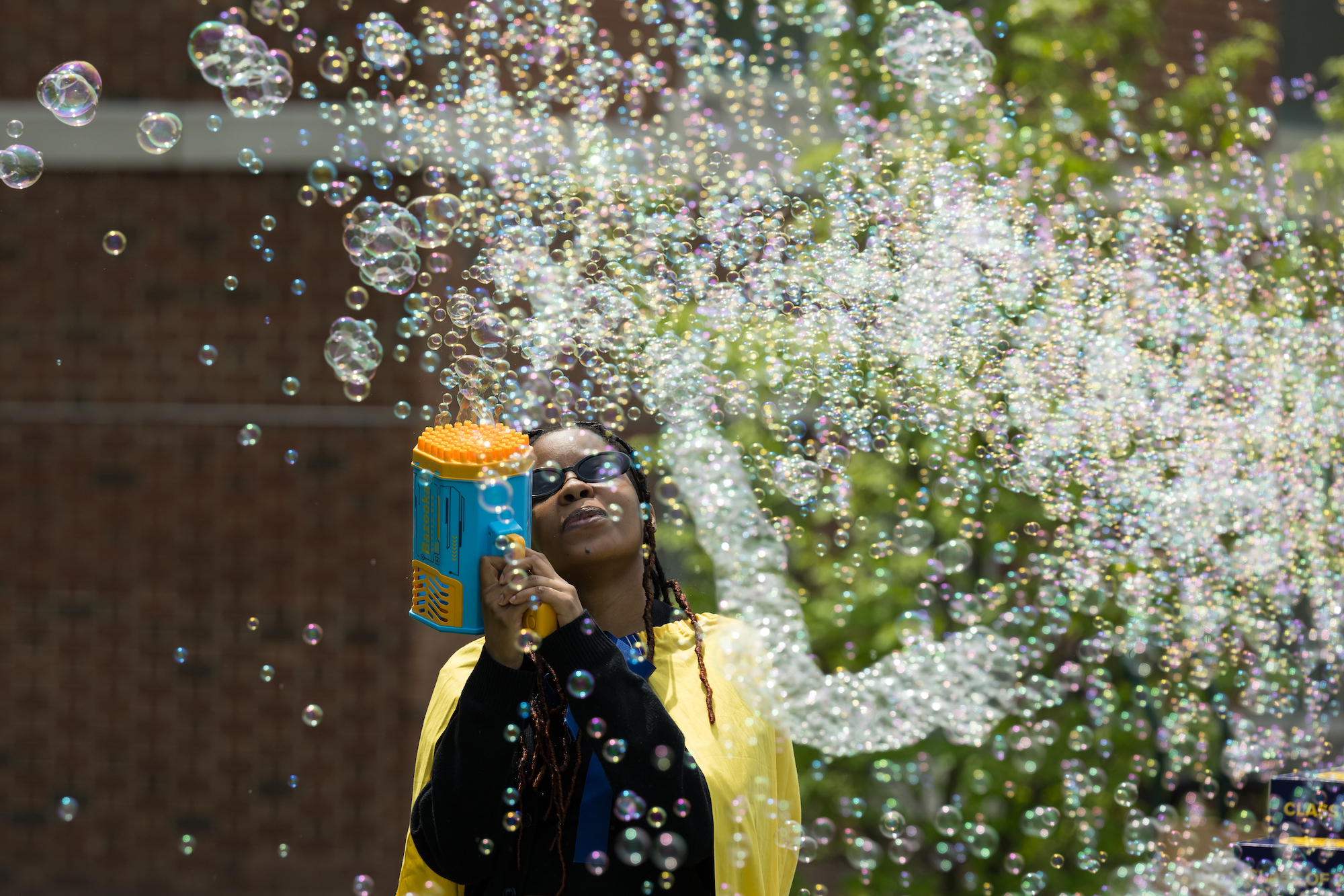 Student blowing massive amounts of bubbles through a bubble gun