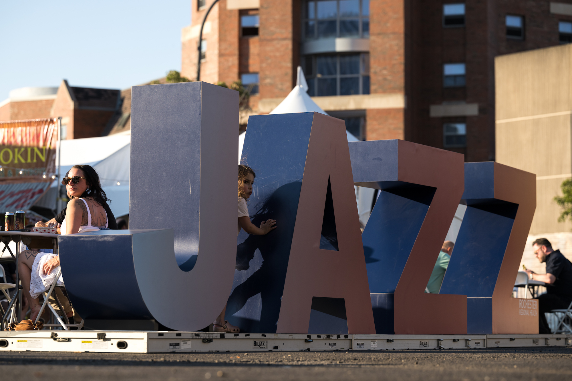 Large metallic letters spelling JAZZ with a young girl sitting between the J and the A