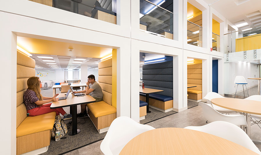 students sitting at brightly lit iZone tables.