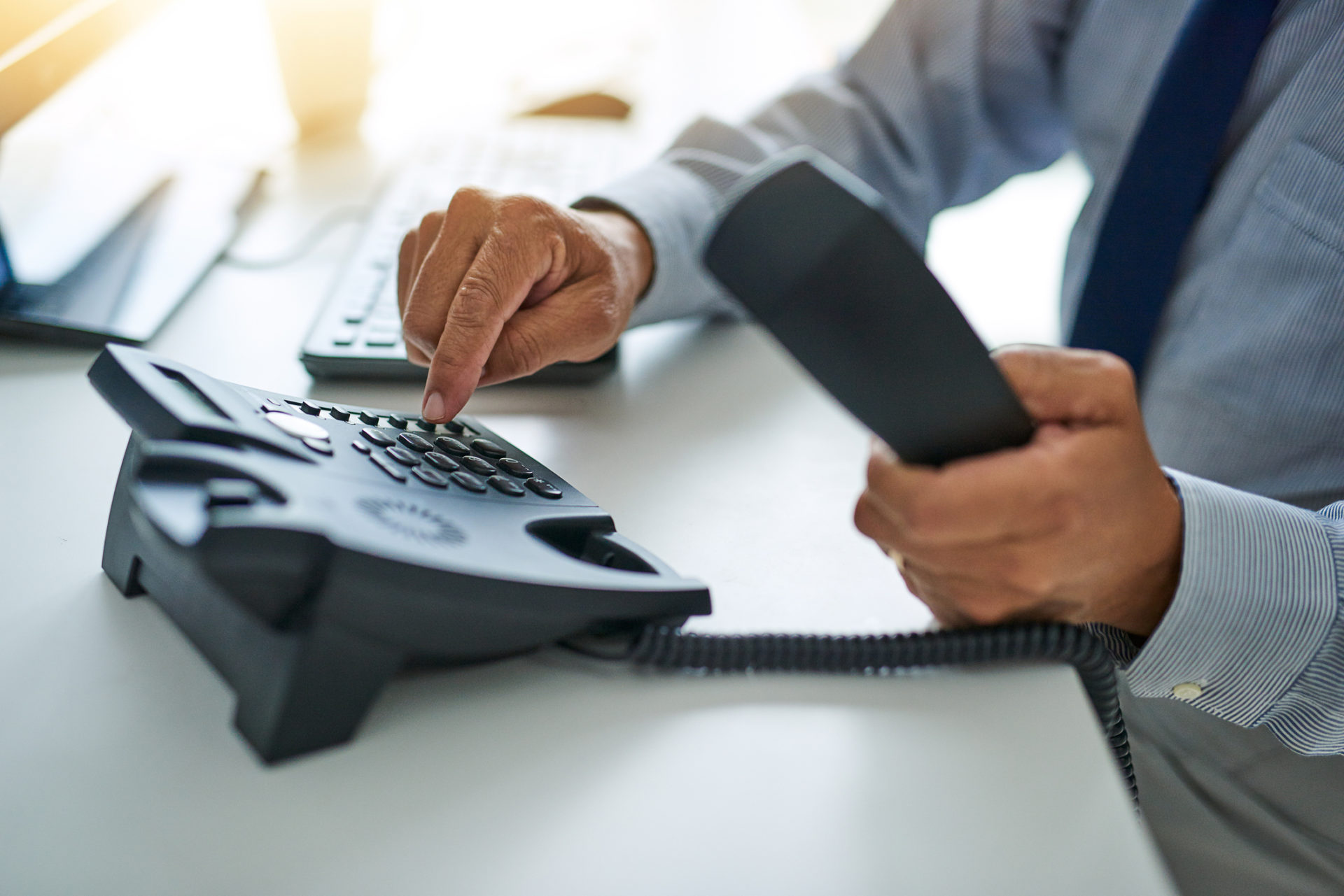 Cropped shot of an unrecognizable businessman dialing a number on a telephone at work