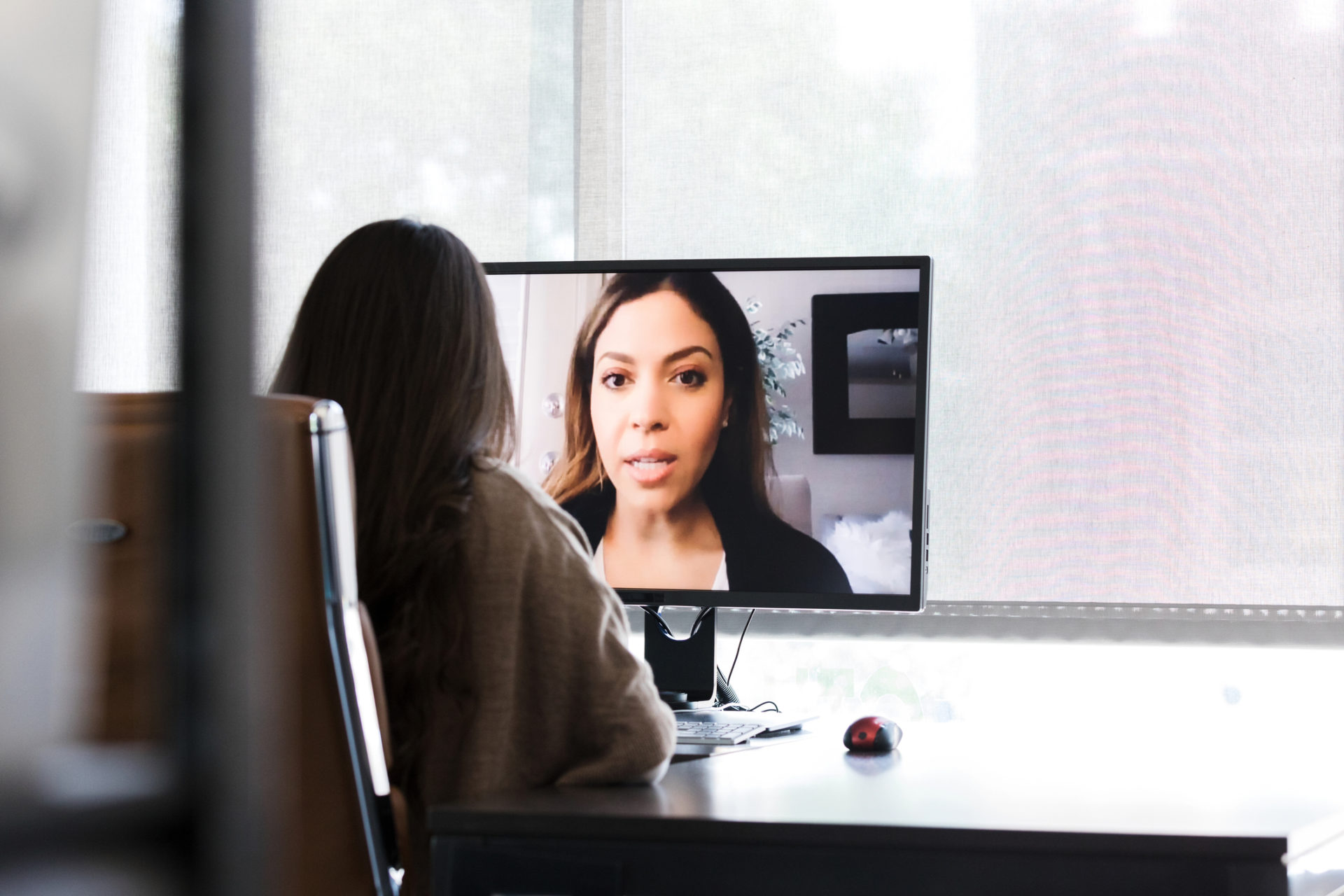 Alone in her office, an unrecognizable woman video conferences with her boss.